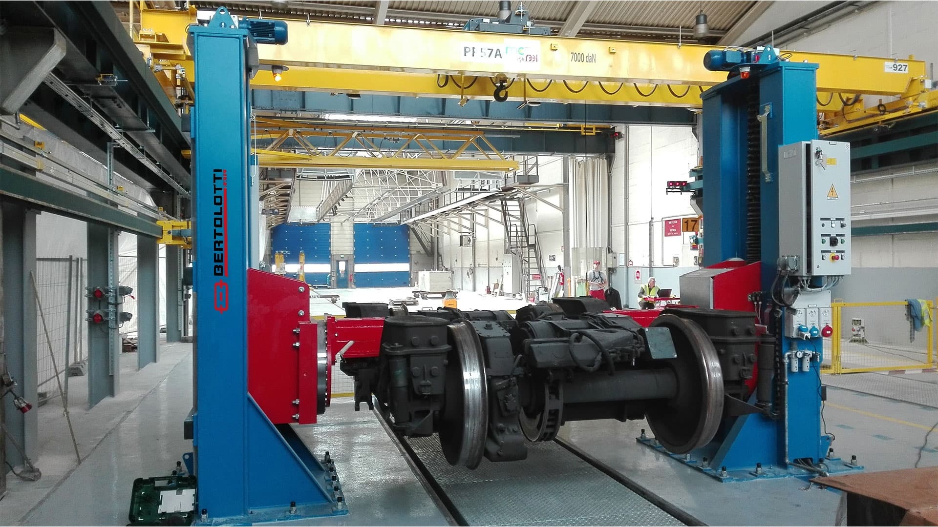 A railway bogie being lifted on blue and red workshop equipment